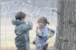  ?? LEONID SHCHEGLOV — BELTA POOL PHOTO VIA AP ?? Migrant children eat near the barbed-wire fence as migrants gather at the Belarus-Poland border near Grodno, Belarus, on Saturday.