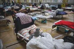  ?? JEFF J MITCHELL/GETTY IMAGES ?? Women and children who have fled war-torn Ukraine rest in a shelter set up in a primary school close to the Ukrainian border in Przemysl, Poland on Monday.