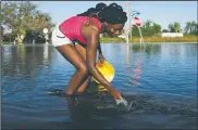  ?? AP/DAVID GOLDMAN ?? Nineve Desronvil, 20, tries to catch fish swimming in the flooded street beside her home Wednesday in the aftermath of Hurricane Irma in Fort Myers, Fla.