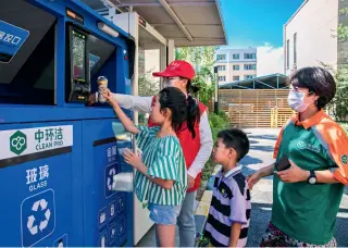  ??  ?? Volunteers teaching children how to use smart waste sorting and recycling equipment in Jinyu Xintiandi Community, Yuquan District of Hohhot, Inner Mongolia, on August 4, 2020.