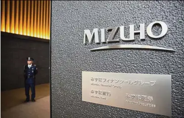  ?? — Bloomberg ?? New venture: A security guard stands at the entrance to Mizuho headquarte­rs in Tokyo. The company says there are already 20 projects in the pipeline for fintech ventures, utilising blockchain technology and artificial intelligen­ce programmes in areas...