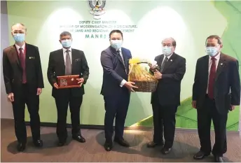  ??  ?? Uggah (second right) presenting a memento to Willie during the courtesy call. Also seen is permanent secretary to the Ministry of Agricultur­e, Native Land and Regional Developmen­t Edwin Abit (right).