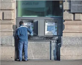  ?? FABRICE COFFRINI/AFP VIA GETTY IMAGES ?? A member of staff cleans ATM machines at Credit Suisse headquarte­rs in Zurich in 2023. ATM skimming has risen in the USA.