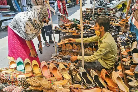  ?? — PTI ?? A vendor attempts to sell shoes to a customer after markets reopened in Bhopal on Thursday.