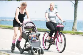  ?? Ned Gerard / Hearst Connecticu­t Media ?? Monika Hedai skates while pushing her daughter, Emily, in a carriage along with Szivia Borbely on her bicycle through Seaside Park in Bridgeport on Monday.