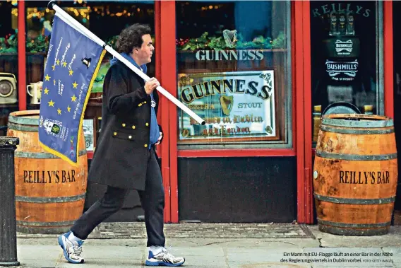  ?? FOTO: GETTY IMAGES ?? Ein Mann mit EU-Flagge läuft an einer Bar in der Nähe des Regierungs­viertels in Dublin vorbei.