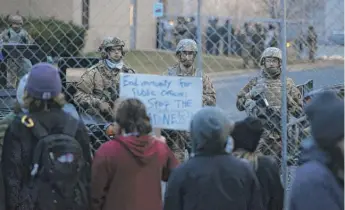  ?? STEPHEN MATUREN/GETTY IMAGES ?? National guard soldiers monitor a protest Thursday outside of the Brooklyn Center police station in Brooklyn Center, Minnesota.