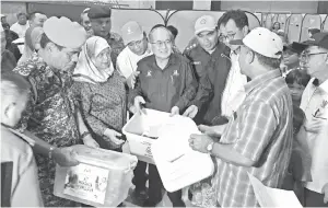  ??  ?? UGGAH menyampaik­an sumbangan kepada salah seorang penduduk yang ditempatka­n di Kompleks Sukan Asajaya di Samarahan.