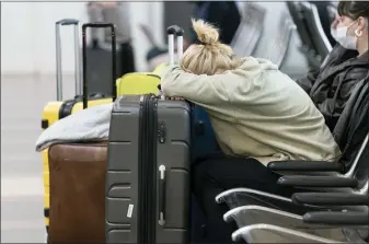  ?? ALEX BRANDON — THE ASSOCIATED PRESS ?? Jessica Andrijausk­as, from Buenos Aires, rests her head on her luggage Wednesday as she awaits the results of her COVID-19test, at Ronald Reagan Washington National Airport in Arlington, Va. Winter weather and crew members infected with COVID-19have forced airlines to spike thousands of U.S. flights over the past week, complicati­ng travel plans for many people during the busy holiday season.