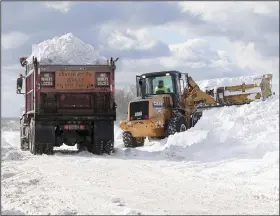  ?? (AP/The Buffalo News/Mark Mulville) ?? Crews truck snow to dump in the parking lot of Erie Community College in Orchard Park on Sunday in Erie County, N.Y.