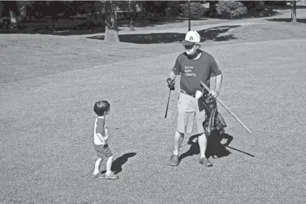  ??  ?? Kimbal Gordon hands his 3-year-old grandson, Walter Cross Gordon, a golf club Thursday at the Links at Galloway.