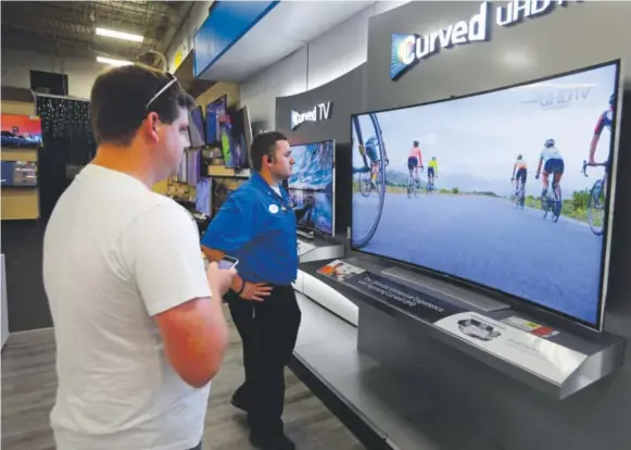  ?? Michael Conroy, The Associated Press ?? JakeWillis, home-theater supervisor at a Best Buy store in Greenwood, Ind., shows customer Landon Leichter a Samsung 78-inch curved TV.