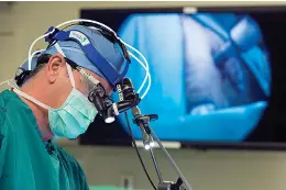  ?? Shawn Rocco/Duke Health via AP ?? ■ Neurosurge­on Dr. John Sampson places a catheter into a glioblasto­ma patient Oct. 28, 2014, at Duke in Durham, N.C. One of the world's most dreaded viruses has been turned into an immune system therapy to fight deadly brain tumors. Survival was better than expected for patients in a small study treated with a modified poliovirus, which helped their bodies attack their cancer, doctors reported on Tuesday.SIDE EFFECTS