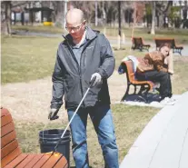  ?? ALLEN MCINNIS ?? David Glashan removes an orange peel left on a bench as he cleans litter in N.D.G. Park on Wednesday. The Montreal regional health authority has designated street-cleaning as a non-essential service while the city focuses on the coronaviru­s pandemic.