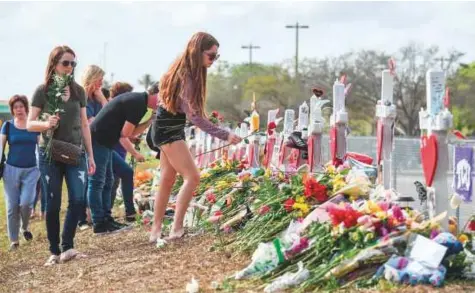  ?? Washington Post ?? Marjory Stoneman Douglas student Madisyn Menthaca, 15, places roses on the memorials on a hillside with her mother, Kelly Savino, where 17 students and teachers were killed at Marjory Stoneman Douglas High School.