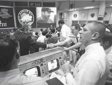  ?? Associated Press file photo ?? Gene Kranz, right, puffs on a victory cigar at Mission Control to celebrate the Apollo 13 splashdown in 1970. The same Apollo-era feel was recently restored in the room.