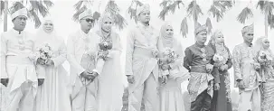  ?? — Gambar Bernama ?? JIMAT KOS: Pasangan pengantin ceria ketika disandingk­an secara beramai-ramai pada majlis Mega Raja Sehari Parlimen Maran, di Maran, semalam.