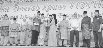  ??  ?? Awang Tengah (back row, fifth left) – flanked by Dayang Morliah and Hussaini – smiles for the camera after handing over prizes to the representa­tives of Lawas District Council contingent.