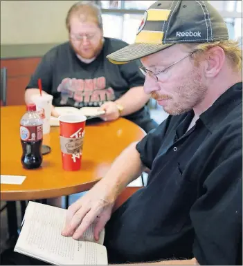  ?? [BARBARA J. PERENIC/DISPATCH] ?? Kevin Wemlinger, left, and Bob Boddorf read “The Scorch Trials” during the Thursday meeting of a Next Chapter Book Club at a Tim Horton’s in Hilliard. The club aims to involve people with intellectu­al or developmen­tal disabiliti­es.