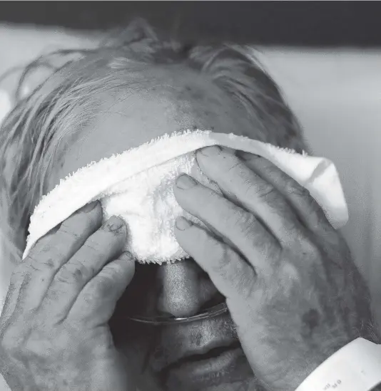  ?? DAVID GOLDMAN AP file ?? A 73-year-old man places a cold compress on his forehead while battling the flu at a hospital in Georgia on Feb. 9, 2018. Doctors can test for the flu and get results within a day, but coronaviru­s testing as of March is still limited in the United States by availabili­ty.