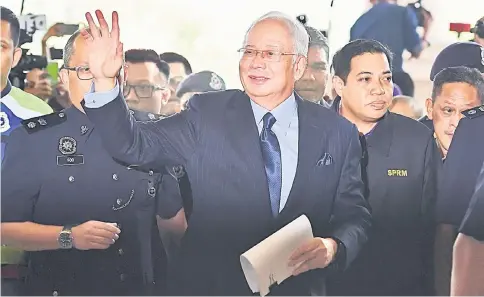  ??  ?? Najib (centre) is escorted by police to the courthouse in Kuala Lumpur. — AFP photo