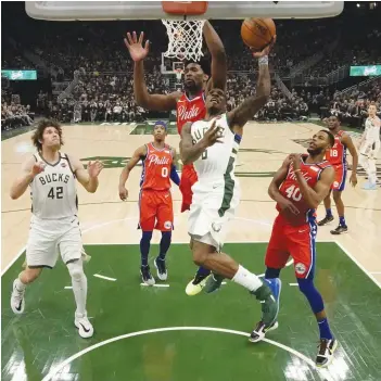  ?? — AP ?? Eric Bledsoe (centre) of Milwaukee Bucks shoots past Philadelph­ia 76ers during their NBA game in Milwaukee on Saturday. The Bucks won 119-98.