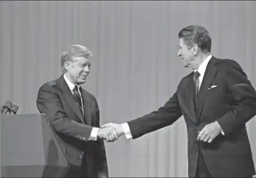  ?? Madeline Drexler/AP File ?? In this Oct. 28, 1980 file photo, President Jimmy Carter shakes hands with Republican Presidenti­al candidate Ronald Reagan after debating in the Cleveland Music Hall in Cleveland. The fall debates are always a big part of any presidenti­al campaign. But...