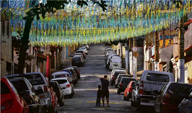  ?? Joel Silva/Folhapress ?? Moradores fotografam rua na zona leste de São Paulo decorada para a Copa do Mundo