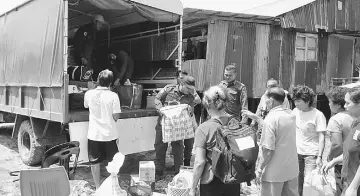  ??  ?? APM Sri Aman personnel help to unload the belongings of Rumah Lembu residents upon their arrival home.