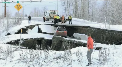 ?? DAN JOLING, THE ASSOCIATED PRESS ?? Highway workers and spectators look at an SUV stuck on a section of an offramp that collapsed during an earthquake Friday morning in Anchorage, Alaska.