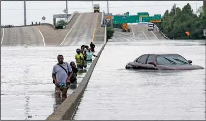  ?? The Associated Press ?? EVACUATION: Evacuees wade down a flooded section of Interstate 610 as floodwater­s from Tropical Storm Harvey rise Sunday in Houston. The remnants of Hurricane Harvey sent devastatin­g floods pouring into Houston Sunday as rising water chased thousands...