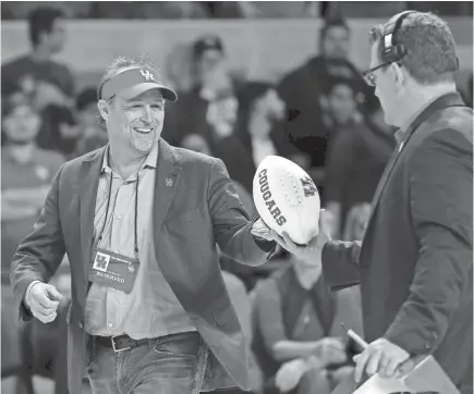  ?? MICHAEL WYKE/AP ?? New football coach Dana Holgorsen gets autographe­d footballs to toss to the crowd at a Houston basketball game.