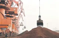  ??  ?? Cranes unload iron ore from a ship at a port in Rizhao, Shandong province. China plans to remove import and export tariffs in 2019 on a range of goods, including import taxes on alternativ­e meals used in animal feed, to secure supplies of raw materials amid trade tensions with the US and boosting outbound cargoes. — Reuters file photo