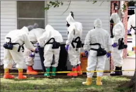  ?? The Associated Press ?? Federal agents wearing hazardous material suits and breathing apparatus inspect the trash can outside the West Hills subdivisio­n house of Paul Kevin Curtis in Corinth, Miss., Friday. Curtis is in custody under the suspicion of sending letters covered...