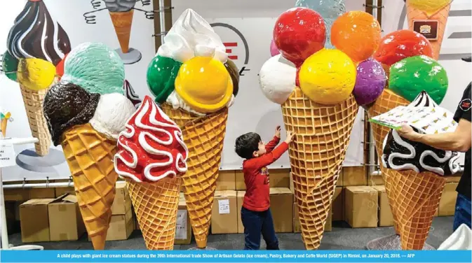 ??  ?? A child plays with giant ice cream statues during the 39th Internatio­nal trade Show of Artisan Gelato (ice cream), Pastry, Bakery and Coffe World (SIGEP) in Rimini, on January 20, 2018. — AFP
