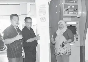  ??  ?? BOLKIAH (tengah) dan Hamid (kiri) bersama seorang wanita dari Kg Saab Dandun yang baru saja mengeluark­an wang tunai dari mesin ATM Bank Rakyat di pintu masuk Hospital Pitas.