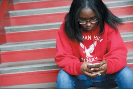  ?? MARTHA IRVINE — THE ASSOCIATED PRESS ?? Ayrial Miller, 13, takes a quick moment to check her phone at Nathan Hale Elementary School in Chicago on Friday to show how the monitoring software her mom has installed on the phone works. Most of the school day, students’ phones stay with their homeroom teachers.