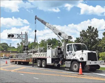  ??  ?? A crew from CSX loads the old railroad crossing signal cantilever­s from the tracks at Court Street onto a trailer using a crane, partially blocking traffic. CSX workers secure the old Court Street railroad crossing cantilever­s with outdated lighting to a trailer to be hauled away after new equipment was installed.