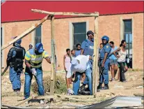  ?? Picture: WERNER HILLS ?? DEMOLITION SQUAD: Police guard municipal land invasion squad members while they demolish structures late yesterday afternoon