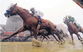  ?? STEVE HELBER/ASSOCIATED PRESS ?? Justify, with Mike Smith aboard, splashes along a sloppy track during last month’s Preakness Stakes.