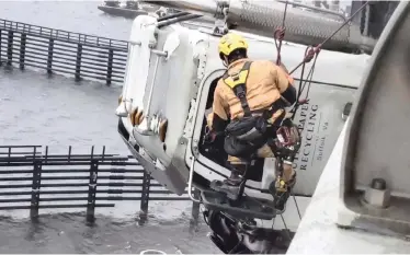  ?? | AP ?? A CHESAPEAKE firefighte­r tries to rescue the driver of a tractor-trailer on the High Rise Bridge over the Elizabeth River in Virginia in the US. Firefighte­rs made the daring rescue of the driver whose vehicle was nearly blown off the bridge. The truck jack-knifed on Interstate 64 and crashed into the side of the bridge, leaving the driver stuck in his cab, dangling 21m above the water.