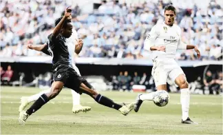  ?? MANU FERNANDEZ AP ?? BRUGGE’S Percy Tau, left, and Real Madrid’s Raphael Varane go for the ball during the Champions League group A soccer match between Real Madrid and Club Brugge, at the Santiago Bernabeu stadium in Madrid. |