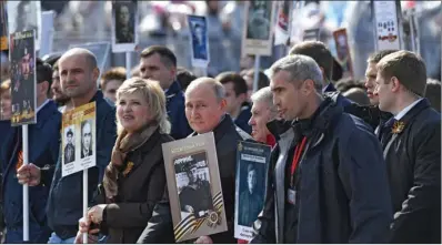  ?? (AFP) ?? Russian President Vladimir Putin (centre) and other participan­ts carry portraits of their relatives — WWII soldiers — as they take part in the Immortal Regiment march on Red Square in central Moscow on Monday.