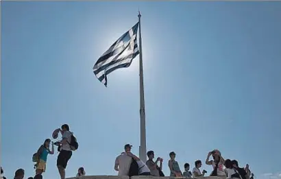  ?? MANÉ ESPINOSA ?? Un grupo de ciudadanos alrededor de una bandera griega, en Atenas