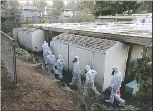  ?? (File Photo/AP/Ted S. Warren) ?? Workers from a Servpro disaster recovery team wearing protective suits and respirator­s enter the Life Care Center on March 11, 2020, in Kirkland, Wash., to begin cleaning and disinfecti­ng the facility near Seattle. The nursing home was at the center of the coronaviru­s outbreak in Washington state at the time.