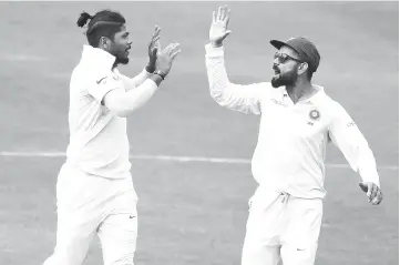  ??  ?? Indian captain Virat Kohli (R) and bowler Umesh Yadav celebrates the dismissal of West Indian cricketer Roston Chase (L) during the third day’s play of the second Test cricket match between India and West Indies at the Rajiv Gandhi Internatio­nal Cricket Stadium in Hyderabad. - AFP photo