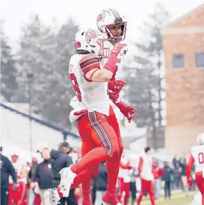  ?? DAVIDZALUB­OWSKI/AP ?? UtahWRBrit­ain Covey, front, celebrates with BryanThomp­son after aTDcatch in Saturday’s victory over Colorado.