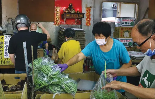  ?? Reuters ?? ↑
A woman arranges vegetables at a shop in Taipei, Taiwan, on Tuesday.