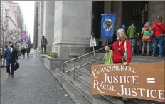  ?? Pittsburgh Post-Gazette ?? Elizabeth Donohoe, of Forest Hills, a member of the Green Party, holds a sign calling for environmen­tal and social justice during a rally Wednesday on the steps of the City-County Building in Downtown. Several dozen people gathered to protest the broken promises by Democrats over the years and to call on President Joe Biden to fulfill those promises.