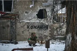  ?? The Associated Press ?? A Ukrainian soldier pets a dog Tuesday in Bakhmut, Donetsk region, Ukraine. The writing on the wall reads “Love.”